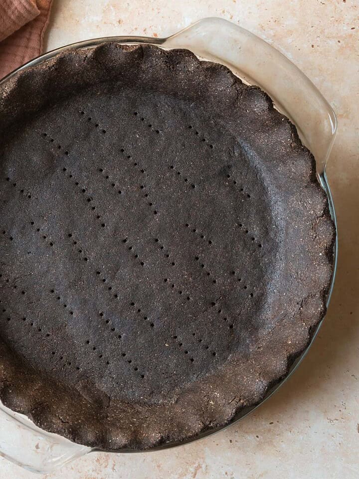 Baked chocolate pie crust on a tan countertop.
