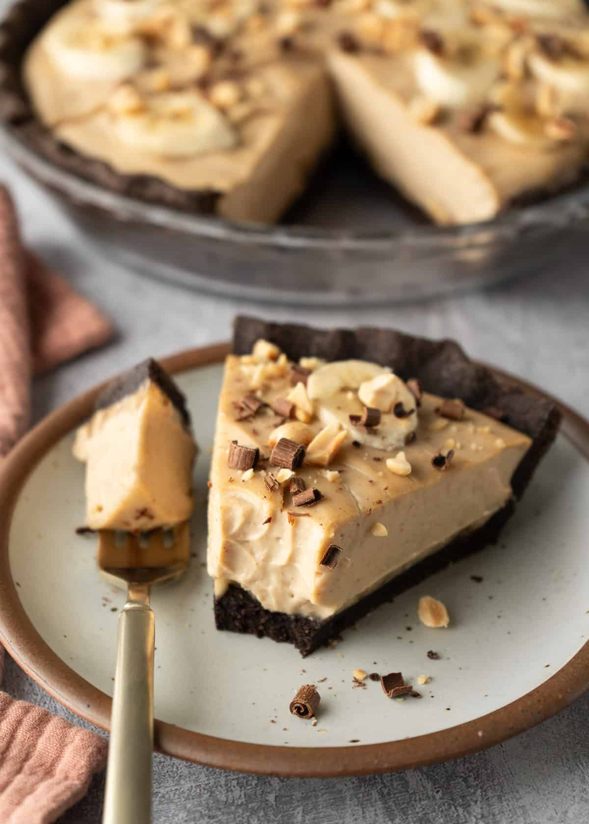 A slice of vegan peanut butter pie on a plate with a bite on fork to show creaminess.