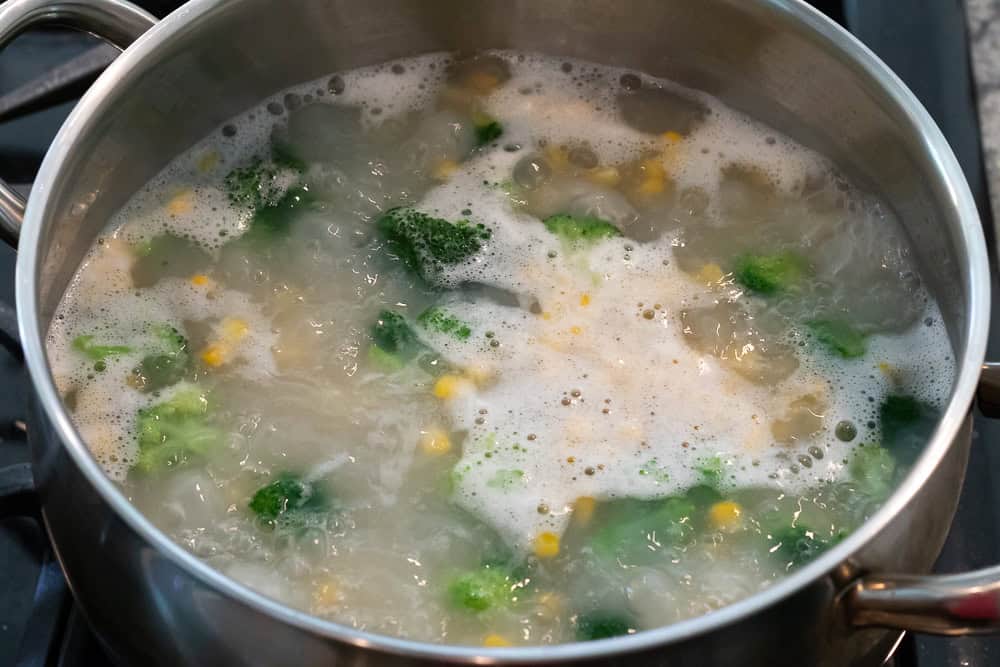 Boiling pasta and veggies together.