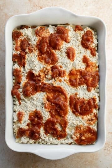 The final layer of vegan ricotta spread on top plus dollops of marinara sauce.