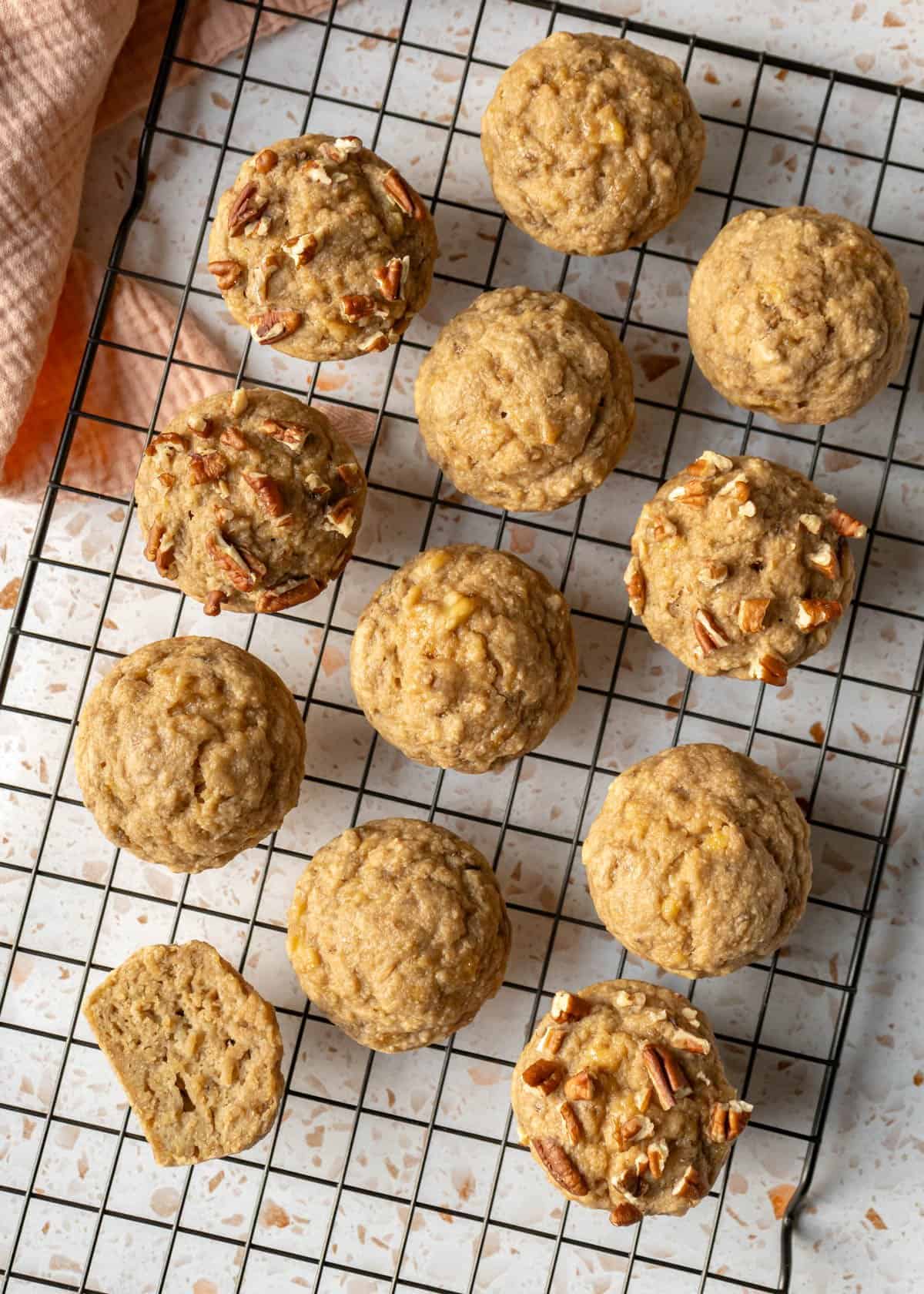 Banana muffins on a cooling rack with some topped with chopped pecans.