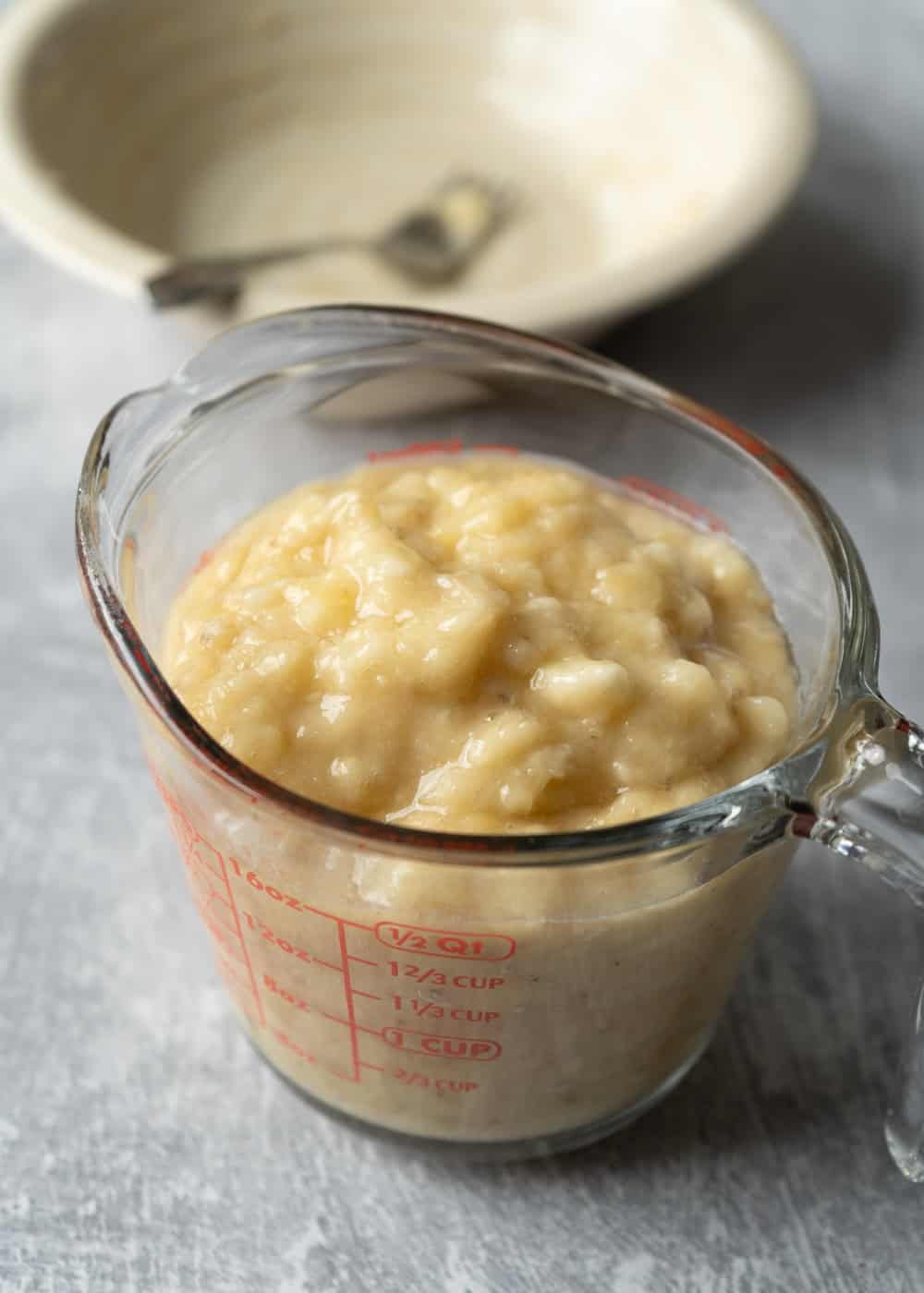 Two and a half cups of mashed banana in a glass measuring cup.