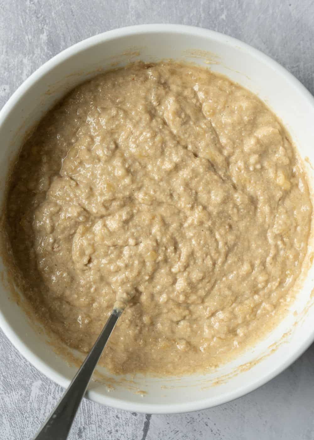 Banana muffin batter in a mixing bowl with a thick and fluffy consistency.