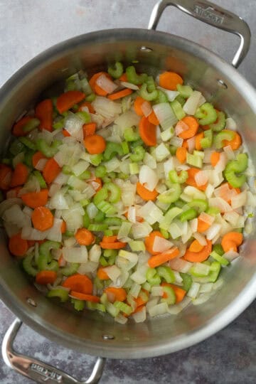 Sauteing onion, celery, and carrot in a soup pot.