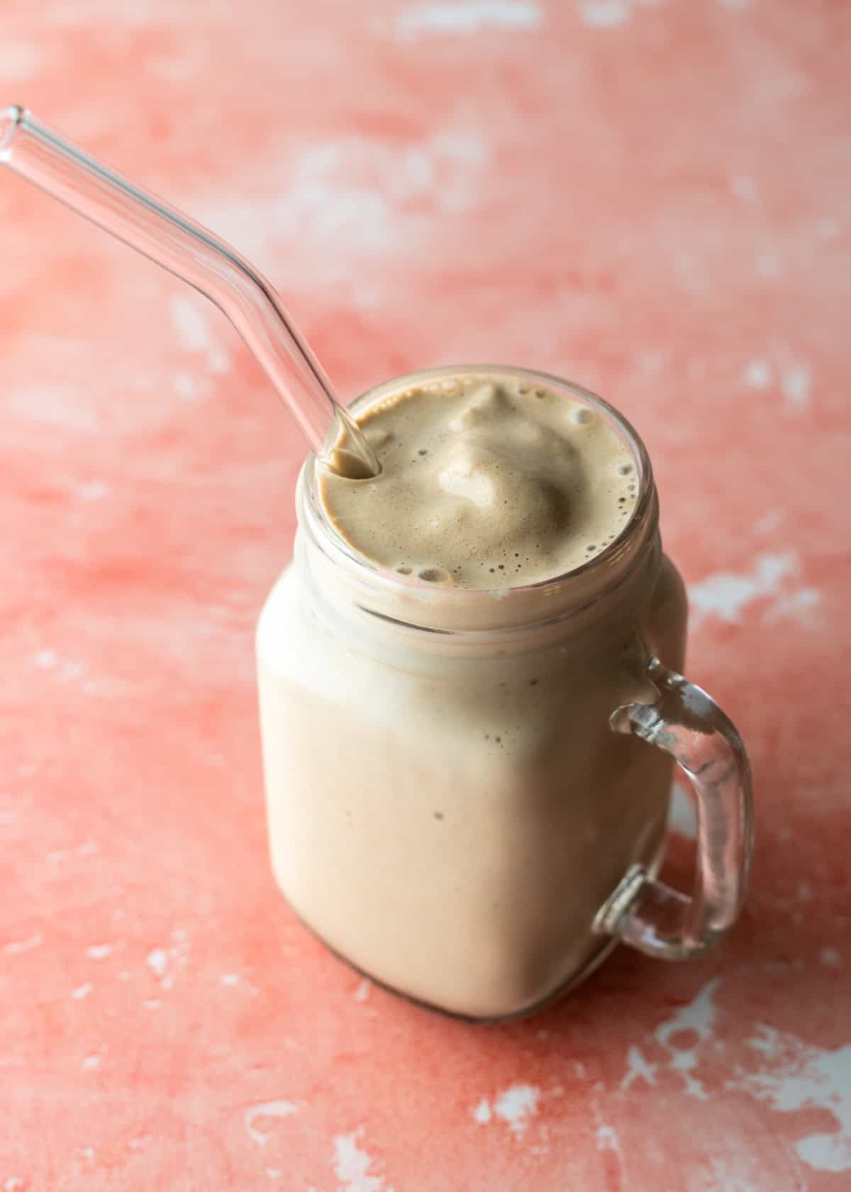 Creamy homemade frappuccino served in a glass with a glass straw.