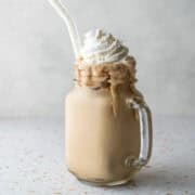 A frosty glass filled with homemade instant espresso frappe and topped with whipped cream.