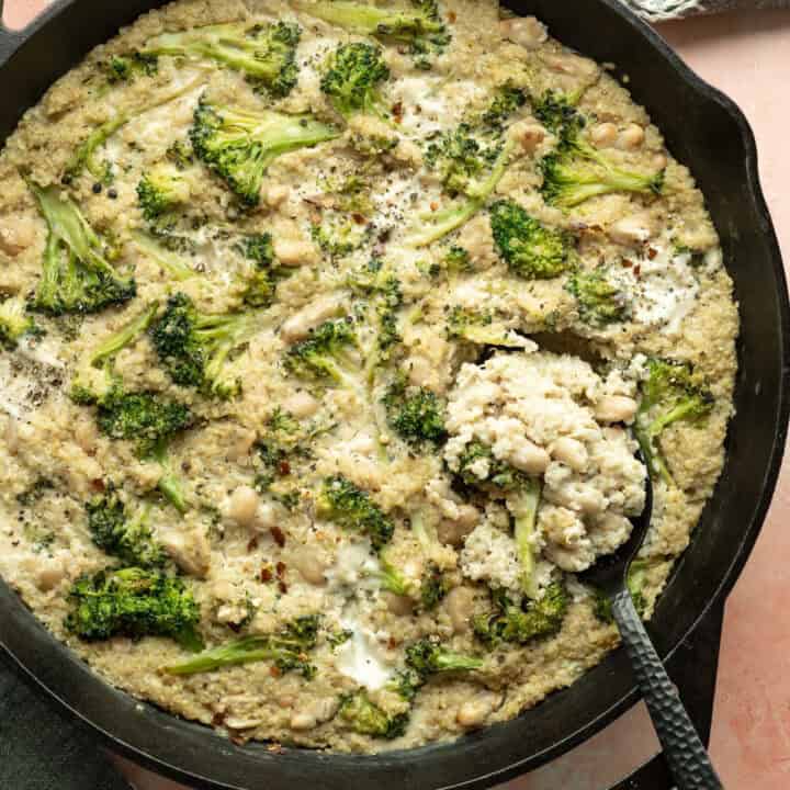 Overhead view of vegan quinoa broccoli casserole in a large cast iron skillet.