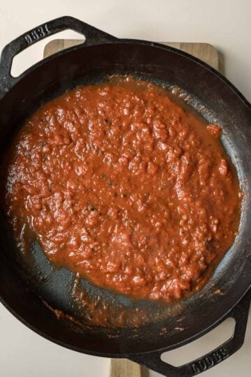 Simmering crushed tomatoes until reduced.