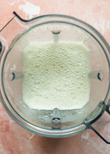 Looking inside a blender at homemade vegan cheese sauce for the casserole.