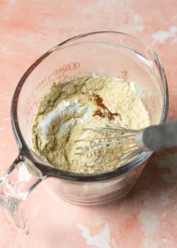Whisking together dry cheesy ingredients in a glass measuring cup.