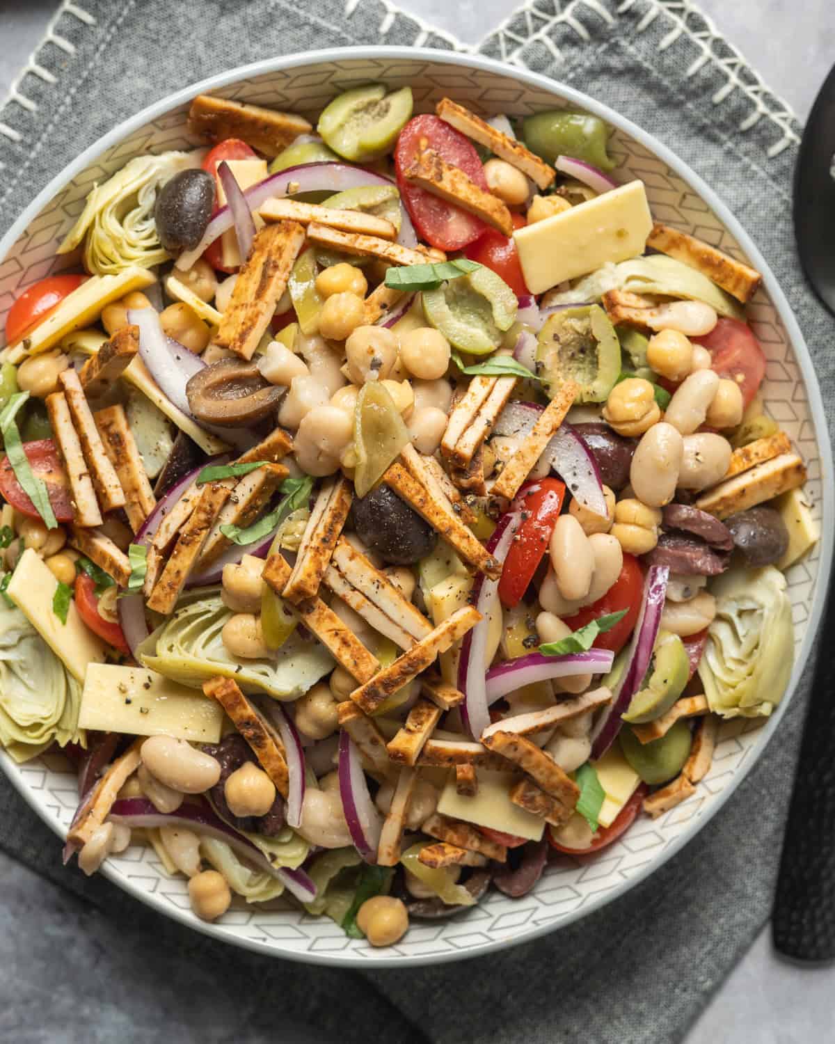 Bean salad tossed with vegan meat and cheese, marinated vegetables, olives, basil, and Italian dressing.