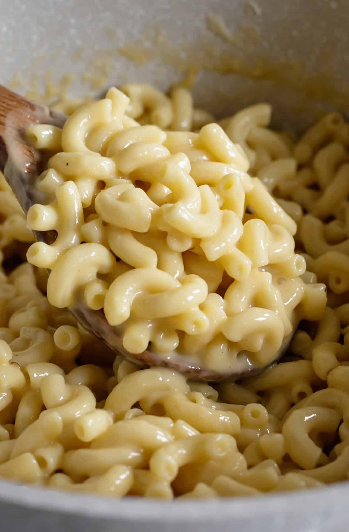 Close up of creamy vegan and mac and cheese being scooped up from a pot.