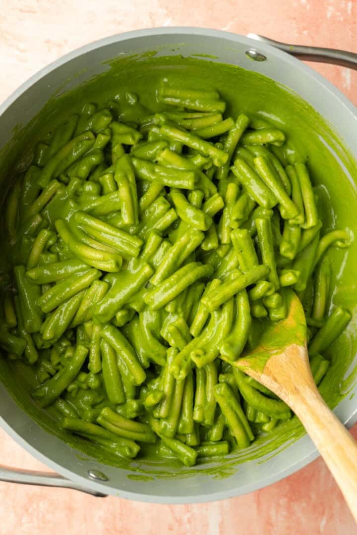 Tossing cooked casarecce pasta with the blended green sauce.