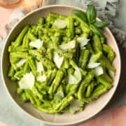 A large bowl filled with creamy green goddess pasta topped with shaved vegan Parmesan.