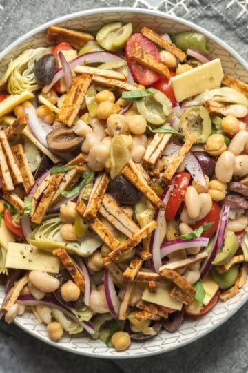 A serving bowl filled with vegan antipasto-inspired bean salad.