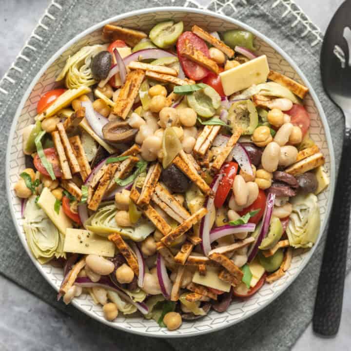 A serving bowl filled with vegan antipasto-inspired bean salad.