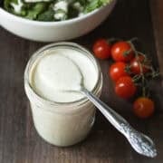 A jar of homemade pepperoncini dressing with a spoon showing creamy texture.