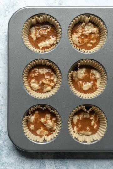 Adding cinnamon swirl to batter in muffin pan.