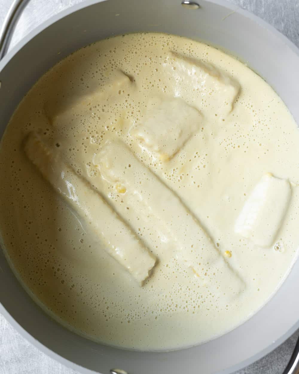 Simmering the ice cream mixture with corn cobs in the pot.