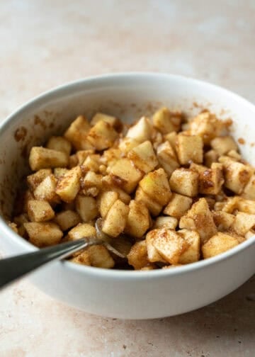 Tossing chopped apple and walnuts with cinnamon and brown sugar in a bowl.