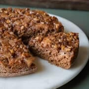 Applesauce cake with apple topping on a cake stand with a slice cut.