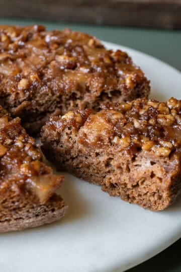 Applesauce cake with apple topping on a cake stand with a slice cut.