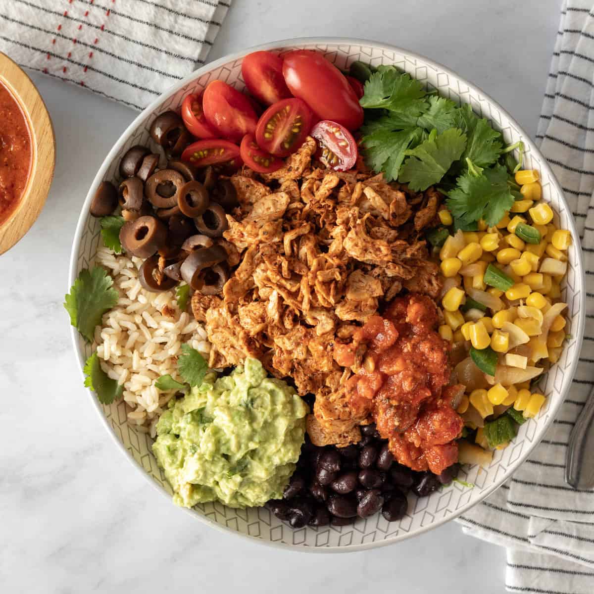 Vegan bowl with rice, beans, guacamole, salsa, taco meat, and other fixings.