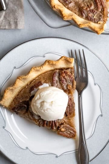 A slice of vegan pecan pie topped with dairy-free ice cream.