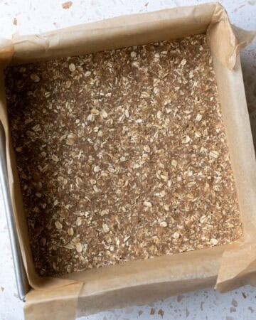 The vegan gluten-free oat crust pressed into an 8-inch square pan lined with parchment.