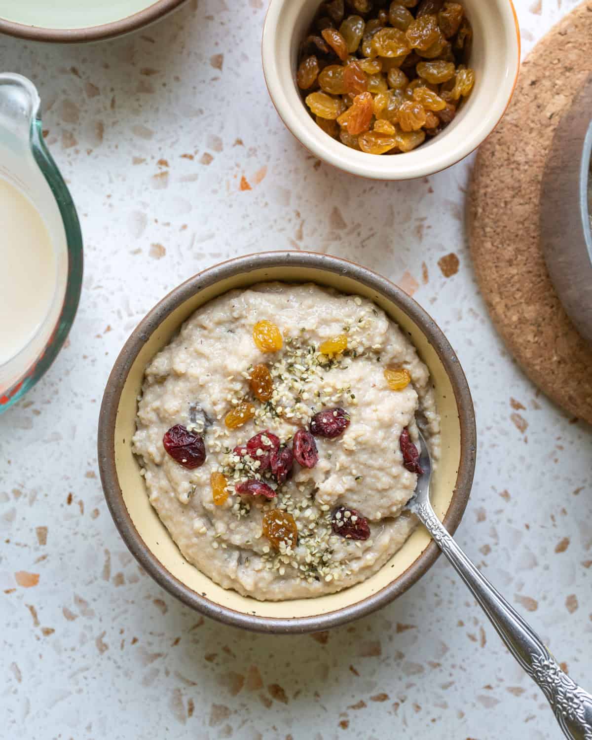A bowl of fonio porridge topped with golden raisins and hemp seeds.