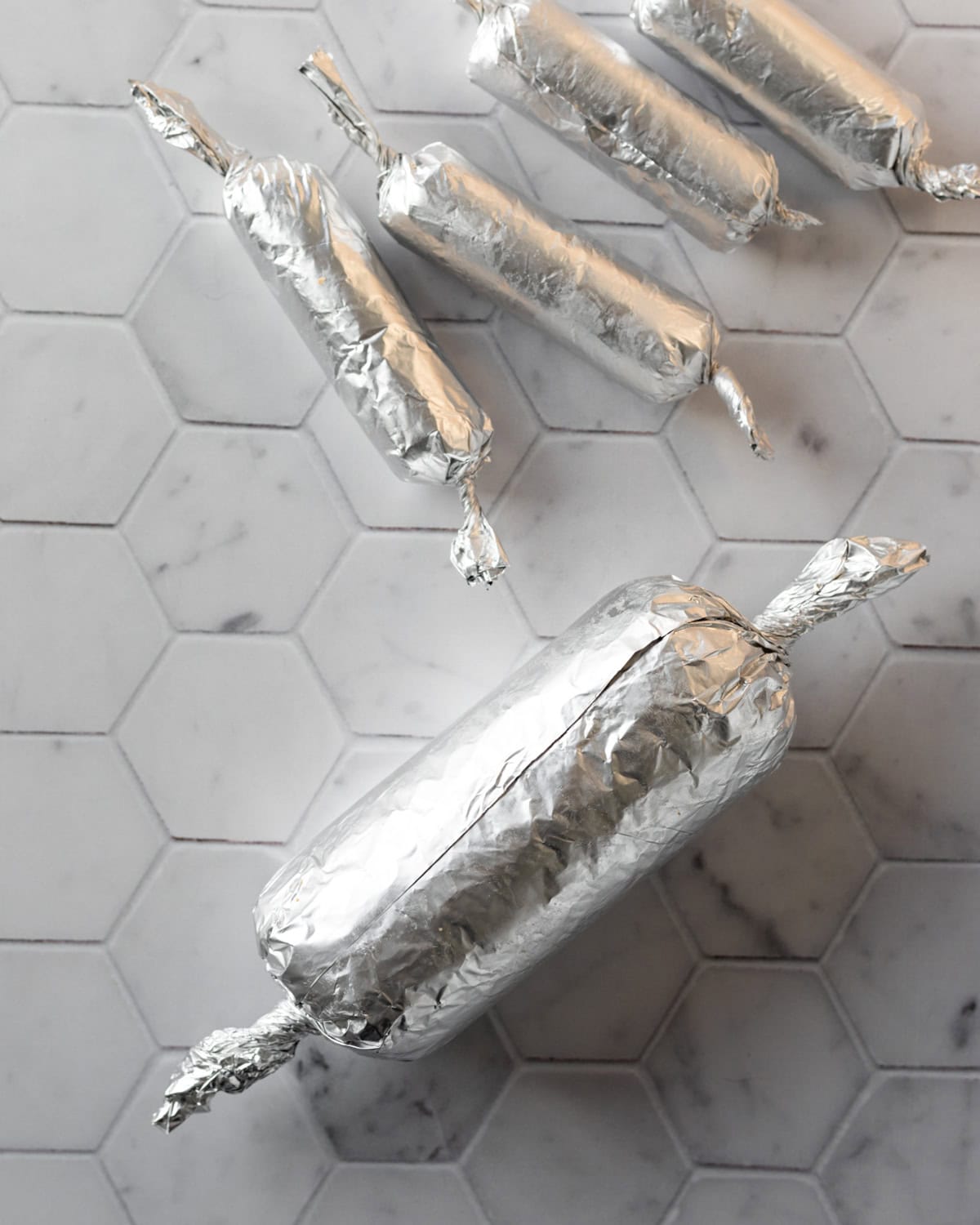 Showing larger and smaller sized breakfast links wrapped in foil.