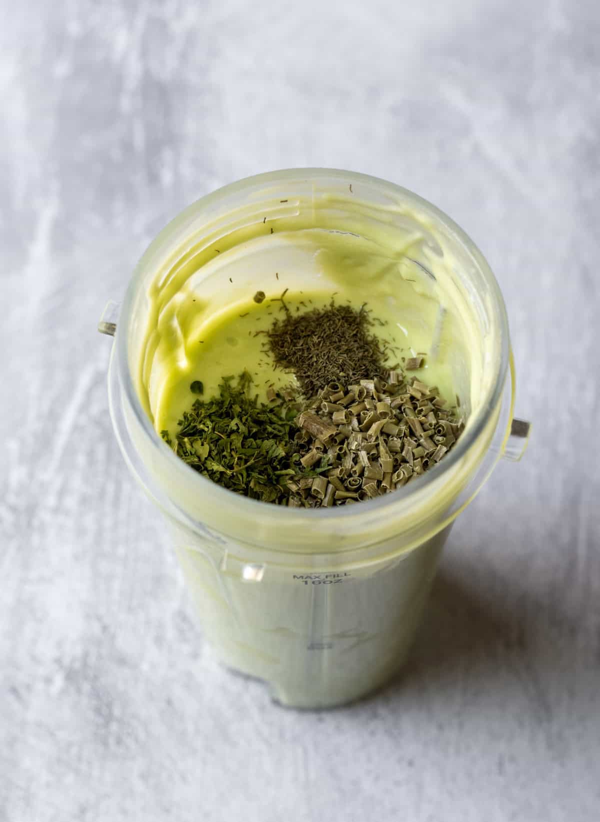 Stirring dried herbs into the blended avocado dressing.