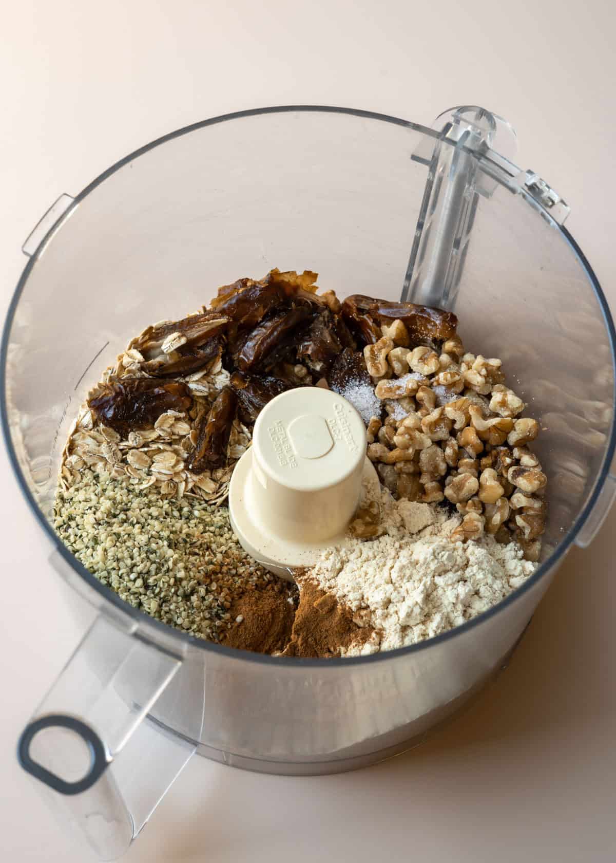 Dates, hemp seeds, walnuts, protein powder, and cinnamon in a food processor.