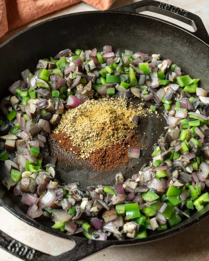Sauteing onion, peppers, and spices in a large skillet.