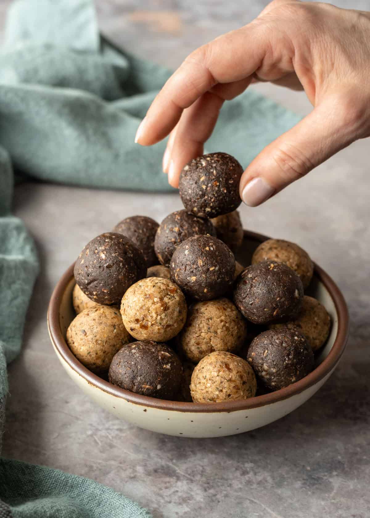 Vanilla and chocolate no-bake protein balls stacked in a small bowl.