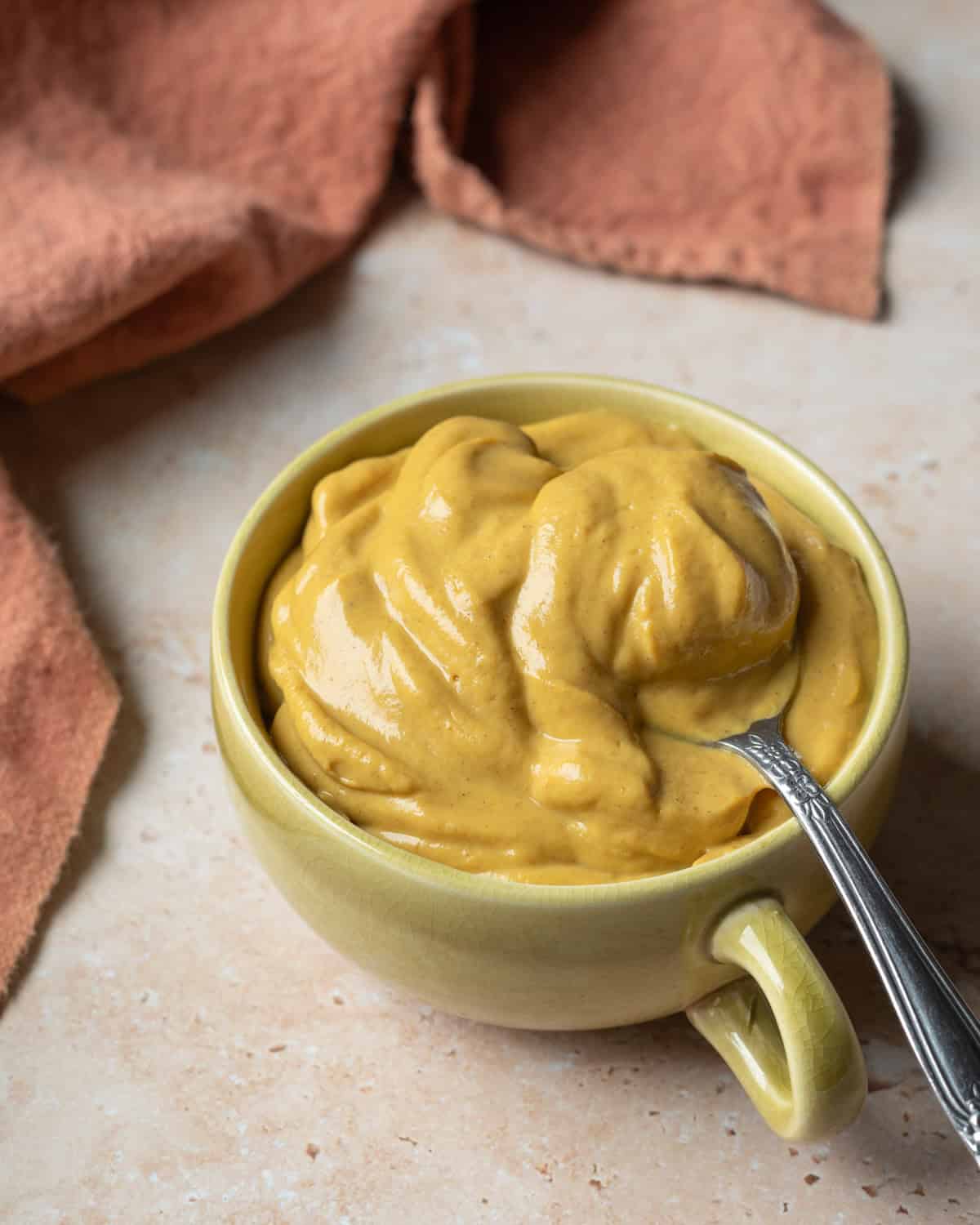 Thick and creamy pumpkin mousse in a cup with a spoon scooping up to show texture.
