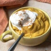 A small tea cup filled with vegan pumpkin mousse topped with non-dairy whipped cream.